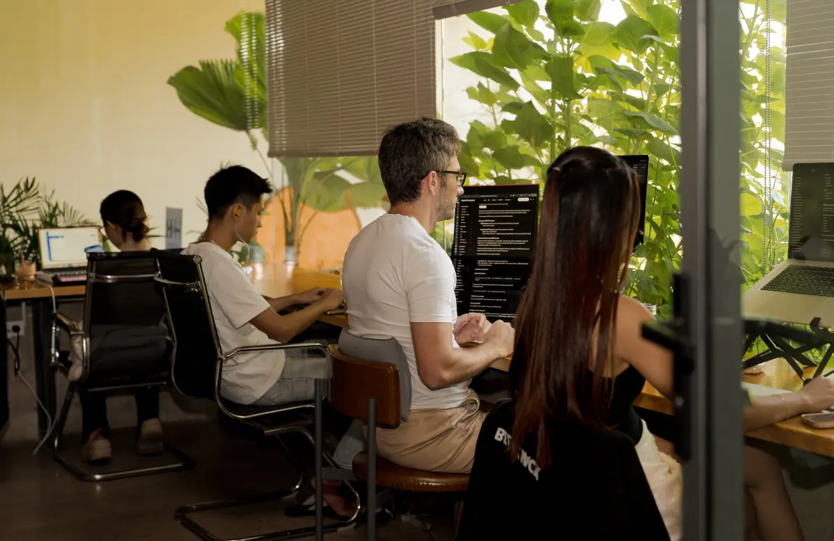 Builders at a window-side desk with laptops and monitors during deep work at a Cursor Da Nang event